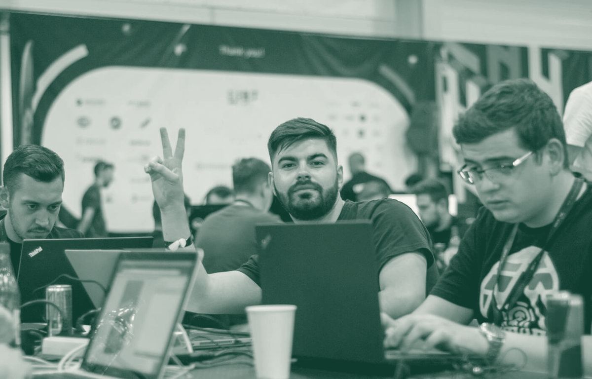 Team members at a hackathon, one flashing a peace sign