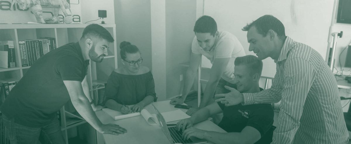 The team gathered around a table in the studio